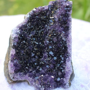 May include: A large amethyst geode with a deep purple color and a rough, natural exterior. The geode is filled with many small, sparkling crystals.