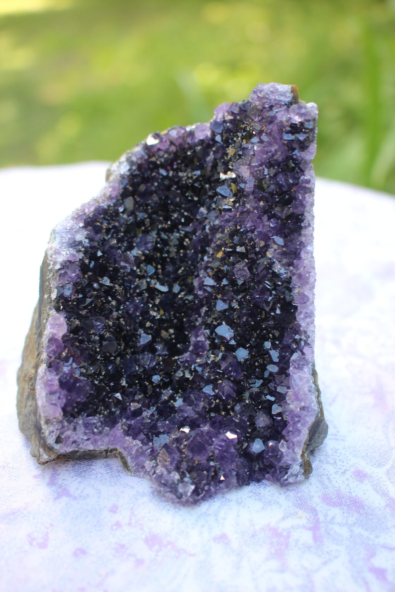 May include: A large amethyst geode with a deep purple color and a rough, natural exterior. The geode is filled with many small, sparkling crystals.