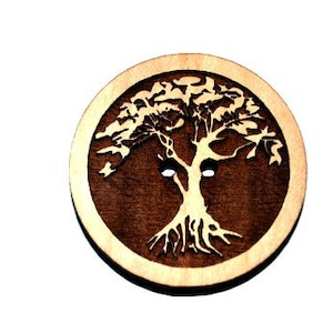 May include: A round wooden button with a tree of life design carved into it. The button is brown with a light wood border.