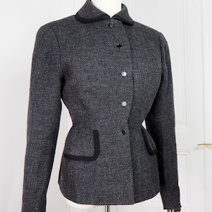 May include: A black and grey tweed blazer with black trim around the collar, pockets, and cuffs. The blazer has a fitted silhouette and features a button closure.