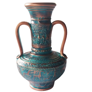 Puede incluir: Un jarrón de cerámica decorativo con dos asas, que presenta un intrincado diseño en relieve en tonos turquesa y cobre.