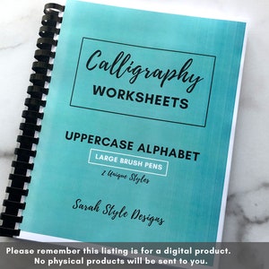 May include: A turquoise blue workbook with a black spiral binding. The cover has the text "Calligraphy Worksheets" in a black box. Below the box, it says "UPPERCASE ALPHABET" in black text. There is a smaller white box with the text "LARGE BRUSH PENS" and "2 Unique Styles" in black text. The bottom of the cover says "Sarah Style Designs" in black cursive text.