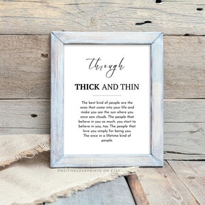 May include: A framed print with the words "Through Thick and Thin" in a decorative font. The text below describes the best kind of people. The frame is light blue and the background is a rustic wood.