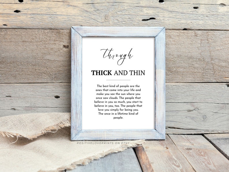 May include: A framed print with the words "Through Thick and Thin" in a decorative font. The text below describes the best kind of people. The frame is light blue and the background is a rustic wood.