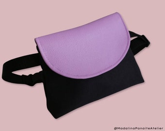 May include: A black and purple fanny pack with a black adjustable strap. The front flap is purple and has a rounded shape.