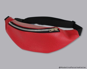 Könnte beinhalten: Eine rote Leder-Bauchtasche mit einem schwarzen verstellbaren Riemen und einem silbernen Reißverschluss.