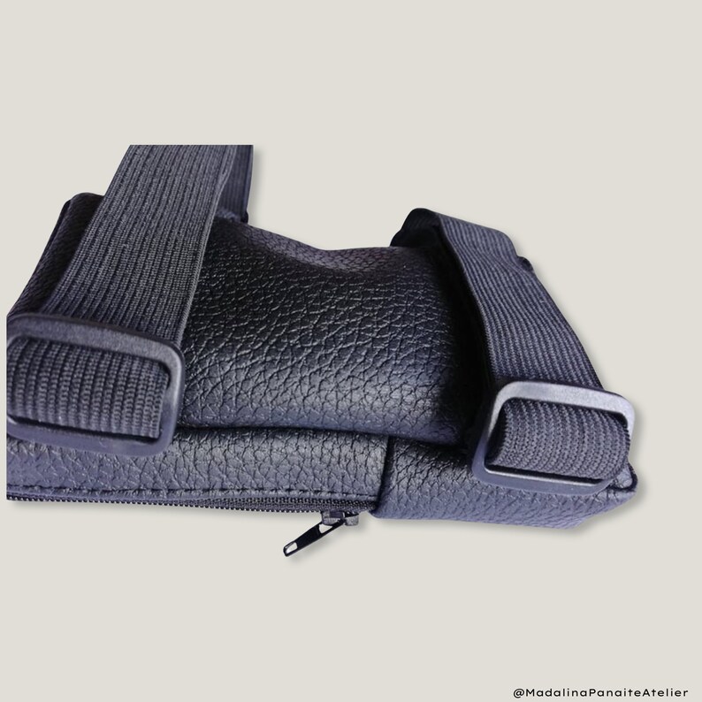 May include: A black leather crossbody bag with a zipper closure and adjustable straps. The bag has a textured surface and a simple design.