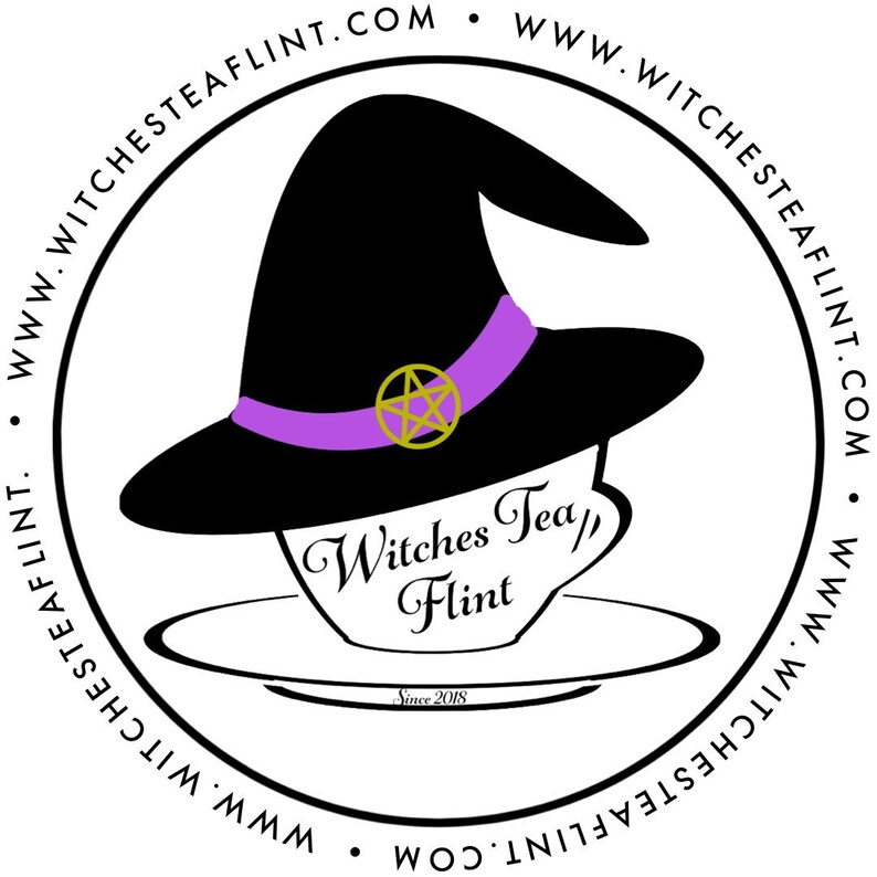 Op de afbeelding: Een zwarte heksenhoed met een paarse band en een gouden vijfpuntige ster zit bovenop een theekopje waarop "Witches Tea/Flint" staat, met daaronder de tekst "Since 2018". De afbeelding is omgeven door een cirkel met de tekst "www.witchesteaFlint.com" die vier keer wordt herhaald.