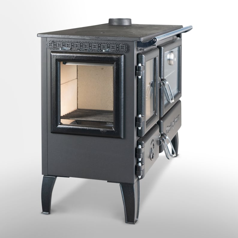 May include: A black cast iron wood-burning stove with a glass door and a side oven. The stove has a decorative design on the top and legs.