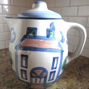 Cafetera con tapa de M.A. Hadley, diseño de casa azul con escena campestre.