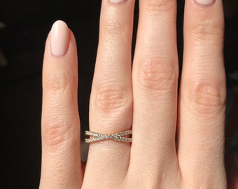May include: A gold ring with a criss-cross design set with small diamonds.