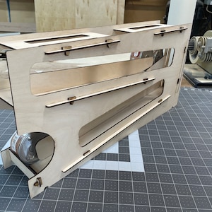 May include: A wooden toy with a ramp and a small wheel at the bottom. The toy is made of light brown wood and has a natural finish.