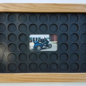 May include: A wooden picture frame with a black background and a grid of 36 round holes. A photo of two people on a motorcycle is in the center of the frame.