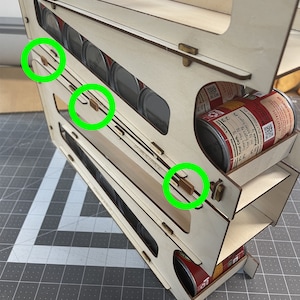 May include: A wooden can rack organizer with three shelves. The shelves are designed to hold cans upright. The rack is made of light wood and has a natural finish. The text "Can Racks Not Included" is printed on the bottom of the rack.
