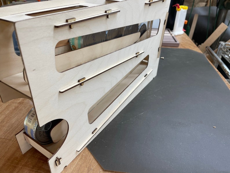 May include: A wooden can dispenser with multiple shelves for storing and dispensing cans. The dispenser is made of light wood and has a natural finish. The dispenser is empty and ready to be filled with cans.