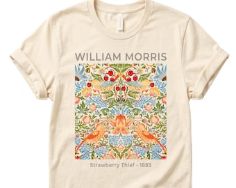 May include: Cream-colored t-shirt featuring a colorful floral and bird design with the text "WILLIAM MORRIS" and "Strawberry Thief - 1883". The design includes red berries, orange birds, and blue foliage.