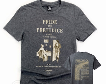 May include: A dark heather grey t-shirt with a vintage-style print of the cover of "Pride and Prejudice" by Jane Austen. The print features a black and white illustration of two people in a room, along with the title of the book, the author's name, and the publication date.