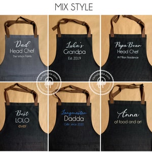 K&ouml;nnte beinhalten: Sechs verschiedene Sch&uuml;rzen aus Denim mit braunen Tr&auml;gern und wei&szlig;em Text. Die Sch&uuml;rzen zeigen verschiedene personalisierte Botschaften, darunter "Dad Head Chef", "Luka's Grandpa", "Papa Bear Head Chef", "Best LOLO ever", "Langmaster Dadda" und "Anna of food and art".