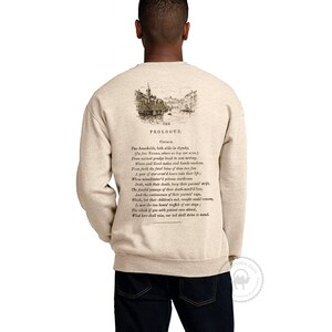 May include: Beige sweatshirt with a vintage illustration of a city scene and text from Shakespeare's Romeo and Juliet. The text reads "The Prologue.  These households, both alike in dignity, (In fair Verona, where we lay our scene) From ancient grudge break to new mutiny, Where civil blood makes civil hands unclean. From forth the fatal loins of these two foes A pair of star-cross'd lovers take their life; Whose misadventured piteous overthrows Doth, with their death, bury their parents' strife. The fearful passage of their death-mark'd love, And the continuance of their parents' rage, Which, but their children's end, nought could remove, Is now the two hours' traffic of our stage; The which if you with patient ears attend, What here shall miss, our toil shall strive to mend."