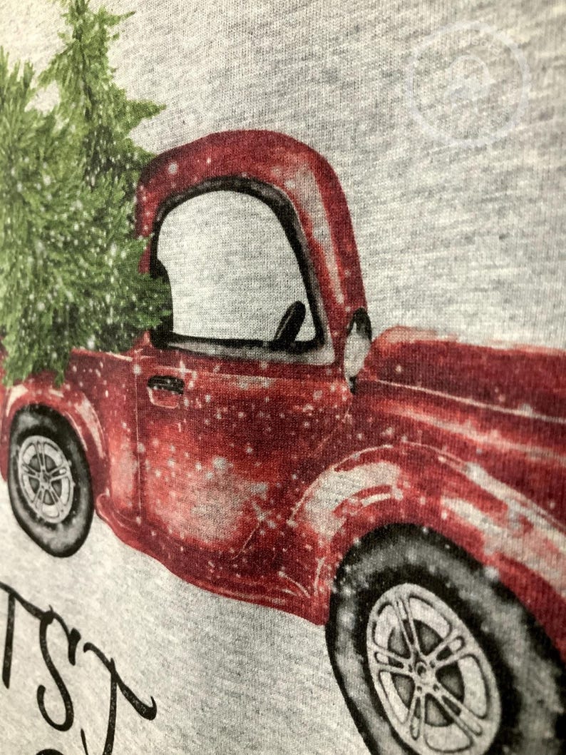 May include: A red vintage truck carrying a green Christmas tree, with a snowy effect, printed on a gray background. The truck has black tires and silver rims. The image has the text "Christmas" in a cursive font.