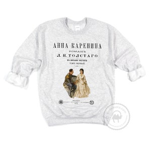May include: A gray sweatshirt with a vintage book cover design featuring the title "Anna Karenina" by L.N. Tolstoy. The cover art depicts a man and woman in 19th-century attire.