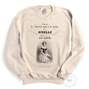 May include: A beige sweatshirt with a vintage-style print of a ballerina in a white dress. The print includes the text "Bansi par M CARLOTTA GRISI & M&Epsilon; &Rho;&Epsilon;&Tau;&Iota;&Rho;&Alpha;. dais GISELLE Balls. Compereur AD.ADAM."