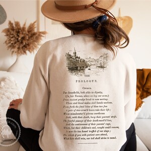 May include: A beige sweatshirt with a vintage illustration of a city scene and text that reads "The Prologue, Chorus. Two households, both alike in dignity, (In fair Verona, where we lay our scene,) From ancient grudge break to new mutiny, Where civil blood makes civil hands unclean. From forth the fatal loins of these two foes A pair of star-cross'd lovers take their life; Whose misadventured piteous overthrows Doth, with their death, bury their parents' strife. The fearful passage of their death-mark'd love, And the continuance of their parents' rage, Which, but their children's end, nought could remove, Is now the two hours' traffic of our stage; The which if you with patient ears attend, What here shall miss, our toil shall strive to mend."