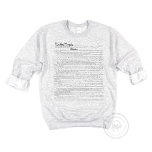 May include: A grey sweatshirt with the full text of the US Constitution printed on the front. The text includes the phrase "We the People" and "Article I".