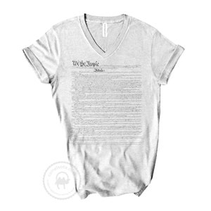 May include: A grey v-neck t-shirt with the full text of the US Constitution printed on the front. The text includes the phrase "We the People" and "Preamble".