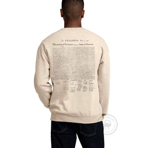 May include: A beige sweatshirt with the full text of the Declaration of Independence printed on the back. The text is in black ink and includes the signatures of the founding fathers.