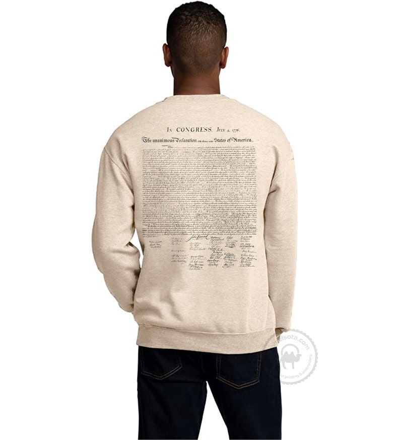 May include: A beige sweatshirt with the full text of the Declaration of Independence printed on the back. The text is in black ink and includes the signatures of the founding fathers.