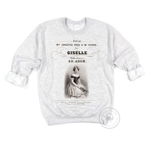 May include: A gray sweatshirt with a vintage-style print of a ballerina in a white dress. The print includes the text "Banse par M CARLOTTA GRISI & &Mu;&Epsilon; &Rho;&Epsilon;&Tau;&Iota;&Rho;&Alpha;. GISELLE Ballet Compos&eacute; par AD.ADAM."