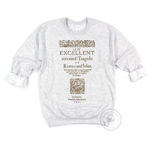 May include: A gray sweatshirt with a vintage-style print of the title page of a play. The title reads "An Excellent Conceited Tragedie of Romco and luliet." The text is in a brown font and is surrounded by a decorative border. The text also includes the date "1597" and the location "London, Printed by John Direct."