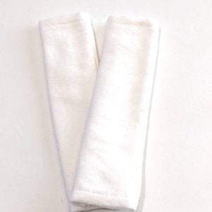 Può includere: Due cinghie in tessuto di cotone bianco, probabilmente per un marsupio o una fascia portabebè.