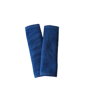 May include: Two blue fabric seatbelt covers with white stitching.
