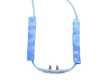 May include: A clear plastic nasal cannula with two prongs and blue fabric tubing. The tubing has a soft, padded section on each side.