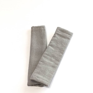 May include: Two gray fabric wrist cuffs, each with a folded edge.