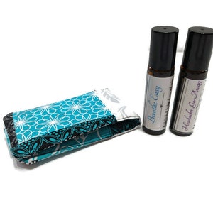 Könnte beinhalten: Zwei kleine Glasflaschen mit schwarzen Kappen und weißen Etiketten. Die Etiketten tragen den Text "Breathe Easy" und "Headache-Go-Away". Die Flaschen liegen auf einem blauen und weißen Stoffbeutel mit Muster.