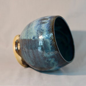 May include: A blue and white ceramic bowl with a speckled glaze. The bowl is slightly tilted and the inside is visible.