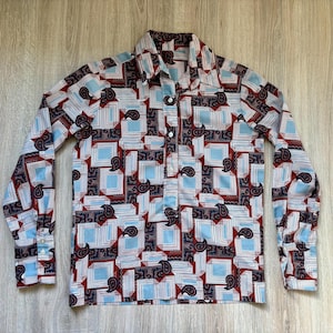 May include: A long-sleeved shirt with a geometric pattern in shades of blue, red, and black. The shirt has a button-up collar and a button-down front.