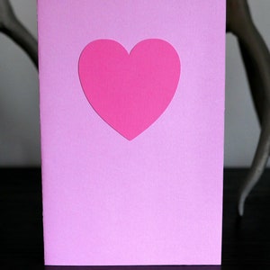 May include: A pink card with a pink heart cut out in the center.