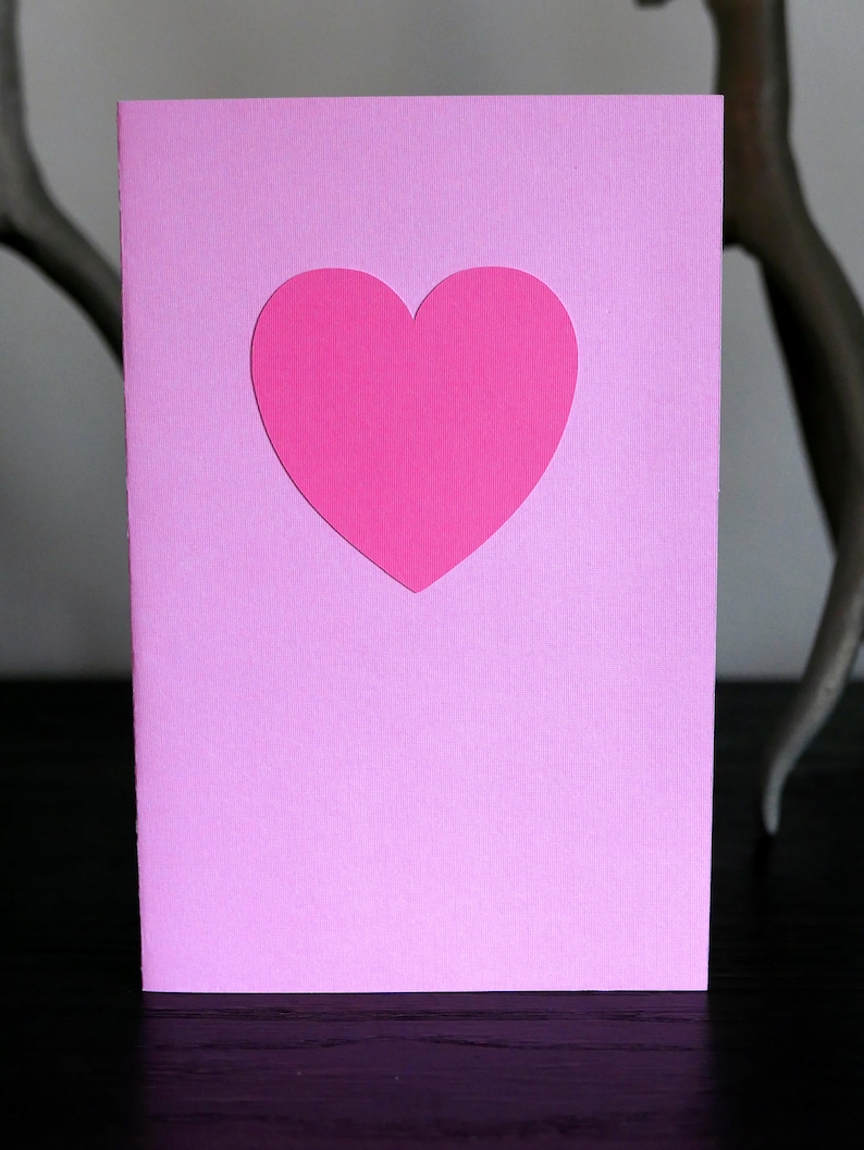 May include: A pink card with a pink heart cut out in the center.