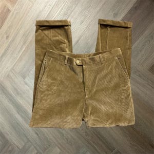 Op de afbeelding: Mosterdgele corduroy broek met een knoopsluiting, riemlussen en voorzakken. De broek heeft een rechte pijp en is omgezoomd. De stof heeft een geribbelde textuur.
