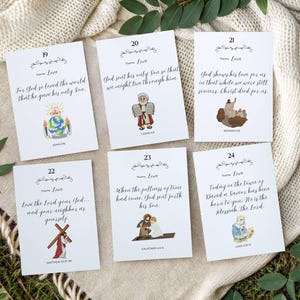 Peut inclure: Six cartes blanches avec des versets bibliques et des illustrations, disposées sur une surface blanche texturée avec de la verdure. Chaque carte présente un verset sur l'amour, avec des accents floraux décoratifs et des références bibliques correspondantes. Les cartes ont les numéros 19-24.