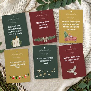 May include: Six cards with inspirational messages, each with a different background colour. The cards have text such as "Smile at five people today" and "Hold the door open for someone." Decorative elements include candles, a truck, and stars.