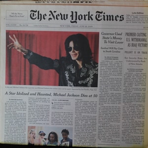 May include: A black and white newspaper front page with a large photo of Michael Jackson with his arm raised. The headline reads "A Star Idolized and Haunted, Michael Jackson Dies at 50".