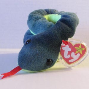 Könnte beinhalten: Ein blau-grünes Plüsch-Schlangenspielzeug mit schwarzen Augen und einer roten Zunge. Das Spielzeug hat ein TY-Etikett. Die Schlange ist aufgerollt und wirkt weich und kuschelig.