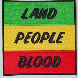 May include: Embroidered patch with a green, yellow, and red striped design. The words "LAND PEOPLE BLOOD" are stitched in black, centered on the patch. The patch has a black border.