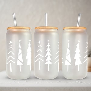 May include: Three frosted glass tumblers with bamboo lids and clear drinking straws. Each tumbler features a white silhouette of a stylized Christmas tree.