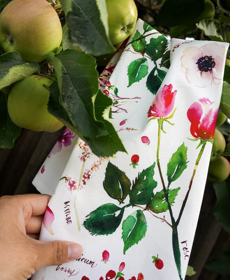 May include: White fabric with a watercolor floral print featuring roses, anemones, and berries. The fabric has the names of the flowers written in cursive on it: "Rose", "Anemone", and "Astilbe".
